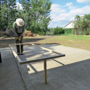 man using an electric drill on the base of the garden bed frame